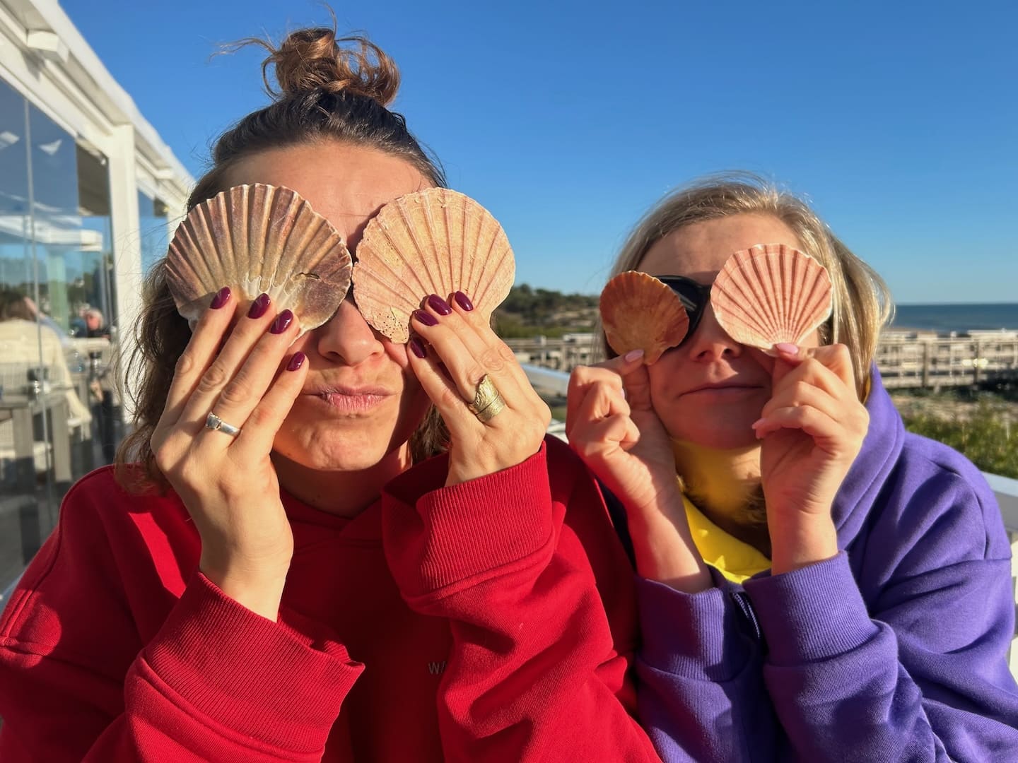 Dwie uśmiechnięte kobiety patrzące przez muszle, symbolizujące różne perspektywy poznawcze w badaniu FRIS i talentach Gallupa.